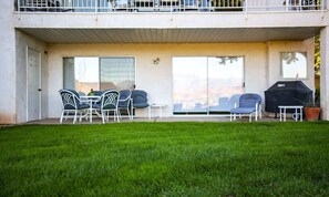 A covered outdoor seating area with chairs and a barbecue grill.