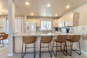Una cocina moderna con una isla central, taburetes de bar y electrodomésticos integrados.