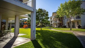 A residential building with a covered patio, outdoor seating, and a playground. - Las Palmas Resort #1214 | All-Inclusive Amenities (Saint George)