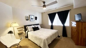 A bedroom with a bed, a chair, a dresser, a ceiling fan, and a window with curtains. - Las Palmas Resort #1214 | All-Inclusive Amenities (Saint George)