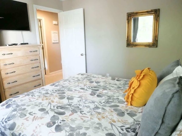 Ein Schlafzimmer mit Bett, Kommode, Fernseher und Spiegel.