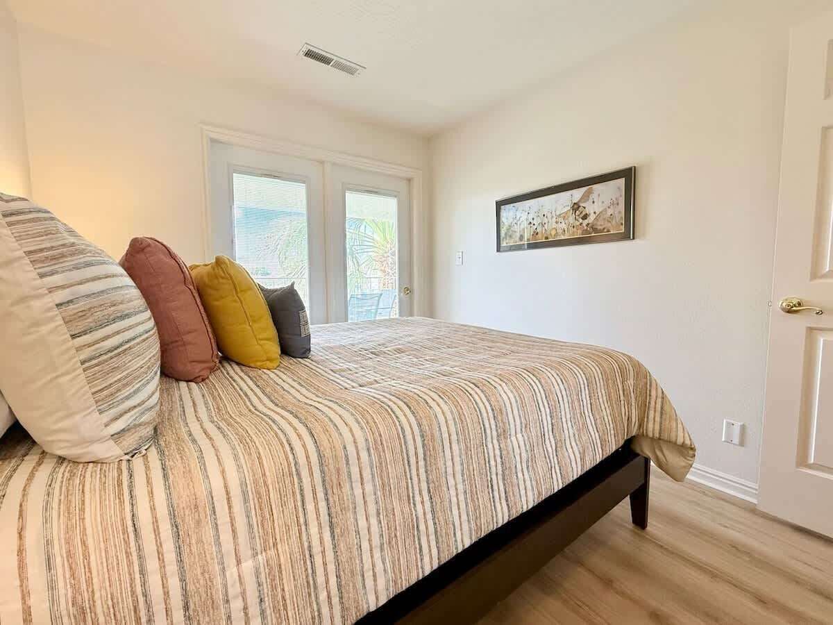 A bedroom with a bed, pillows, a window, and a door.