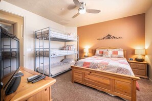 A bedroom with bunk beds, a wooden bed, a desk with a computer, and a ceiling fan. - Las Palmas Resort #1904 | All-Inclusive Amenities (Saint George)
