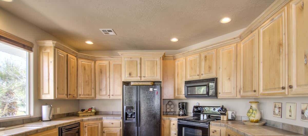 A kitchen with wooden cabinets, a refrigerator, a microwave, and a stove.