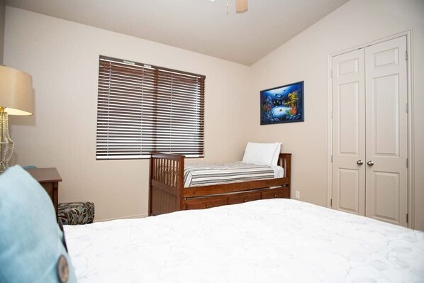 A bedroom with a single bed, a window with blinds, a painting on the wall, and a wardrobe. - Las Palmas Resort #1910 | All-Inclusive Amenities (Saint George)