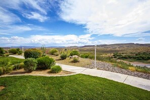A landscaped garden with a pathway, shrubs, and a view of distant hills.