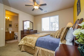 A bedroom with a bed, a ceiling fan, a window, and a nightstand.