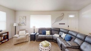 A living room with a sectional sofa, a recliner, a side table, and a lamp.