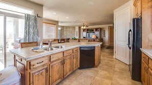 A spacious kitchen with a large island, wooden cabinets, and a built-in dishwasher.