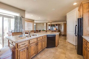 A spacious kitchen with a large island, wooden cabinets, and a built-in dishwasher. - Las Palmas Resort #2107 | All-Inclusive Amenities (Saint George)