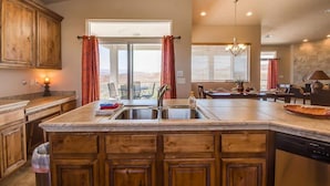 A kitchen with wooden cabinets, a central island with a sink, and a dining area with a chandelier.