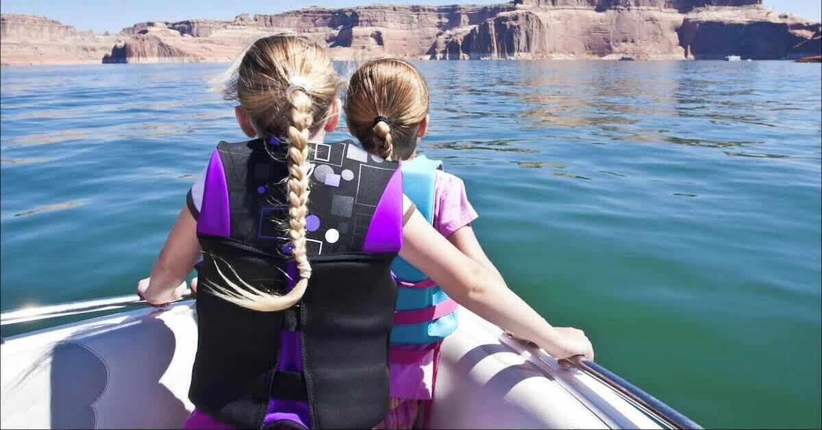 Two individuals on a boat with a rocky landscape in the background.