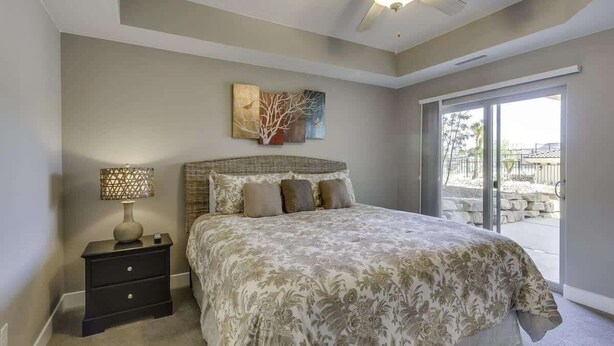 A bedroom with a bed, a nightstand, a lamp, and a ceiling fan.