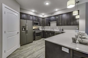 A modern kitchen with dark cabinets, stainless steel appliances, and a large island with bowls.