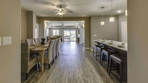 A spacious kitchen with a long counter, bar stools, and a dining area with wicker chairs.