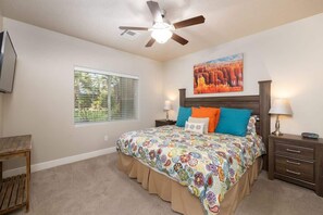 A bedroom with a bed, a ceiling fan, a window, and a painting on the wall. - Estancia Pool Resort #S101 | Poolside View (Saint George)