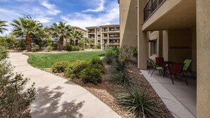 A courtyard with a paved walkway, palm trees, and a building with balconies.