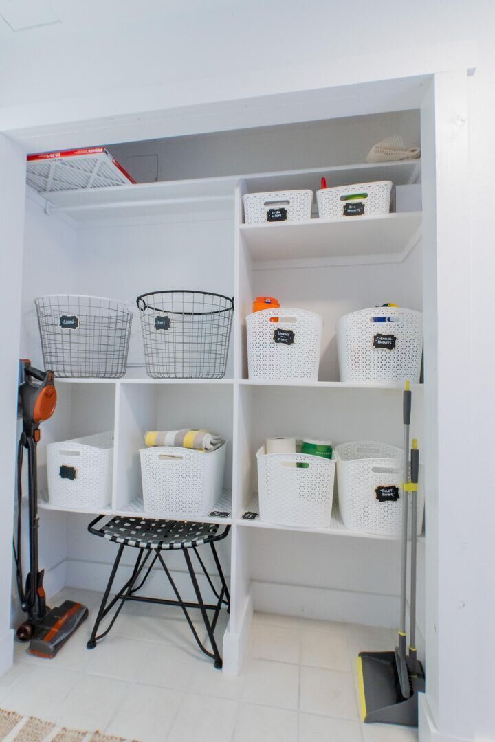 A storage area with shelves and baskets, a vacuum cleaner, and a cleaning mop.