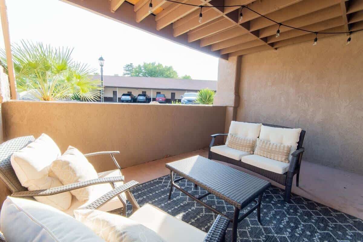 Un espacio al aire libre con patio amoblado con muebles de mimbre, incluyendo un sofá y sillas, y una mesita.