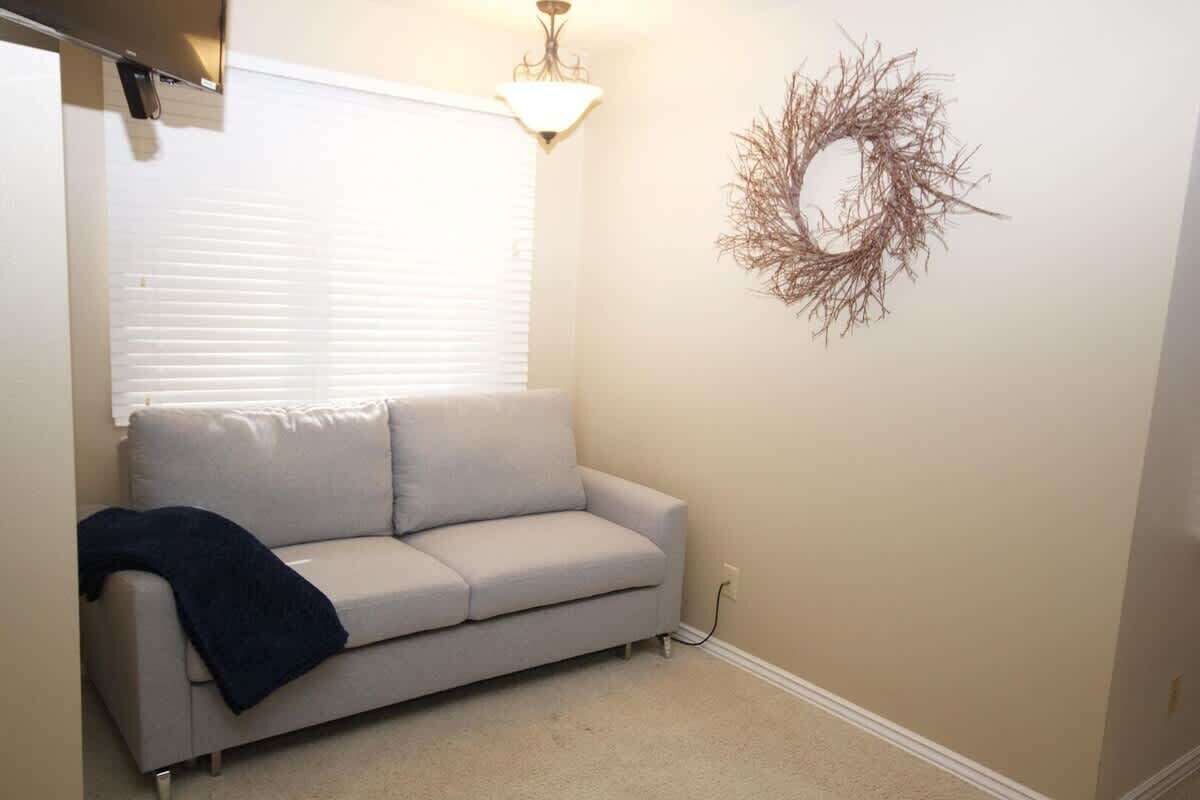 Une pièce avec un canapé beige, un luminaire fixé au mur et une couronne décorative.