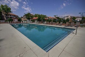 A swimming pool with lounge chairs and a clear sky.