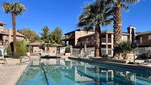 A swimming pool with clear water, surrounded by palm trees and a building with balconies. - Sports Village Resort #H9 | All Amenities Included (Saint George)