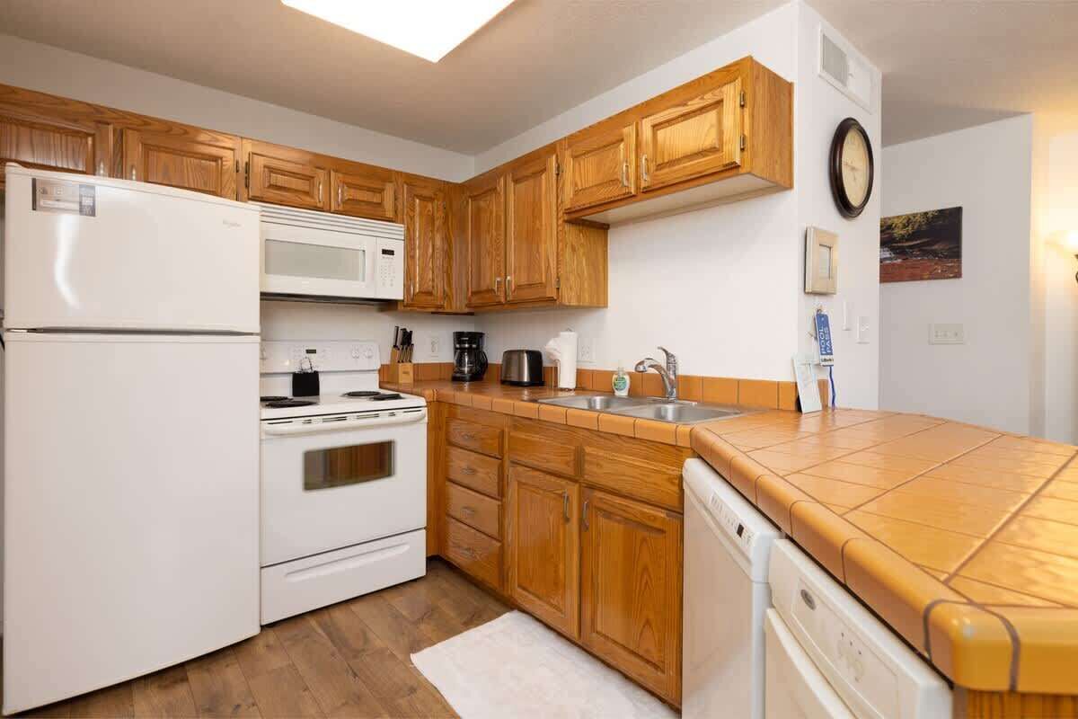 Eine Küche mit Holzschränken, einem Kühlschrank, Herd, Mikrowelle und einem Geschirrspüler.