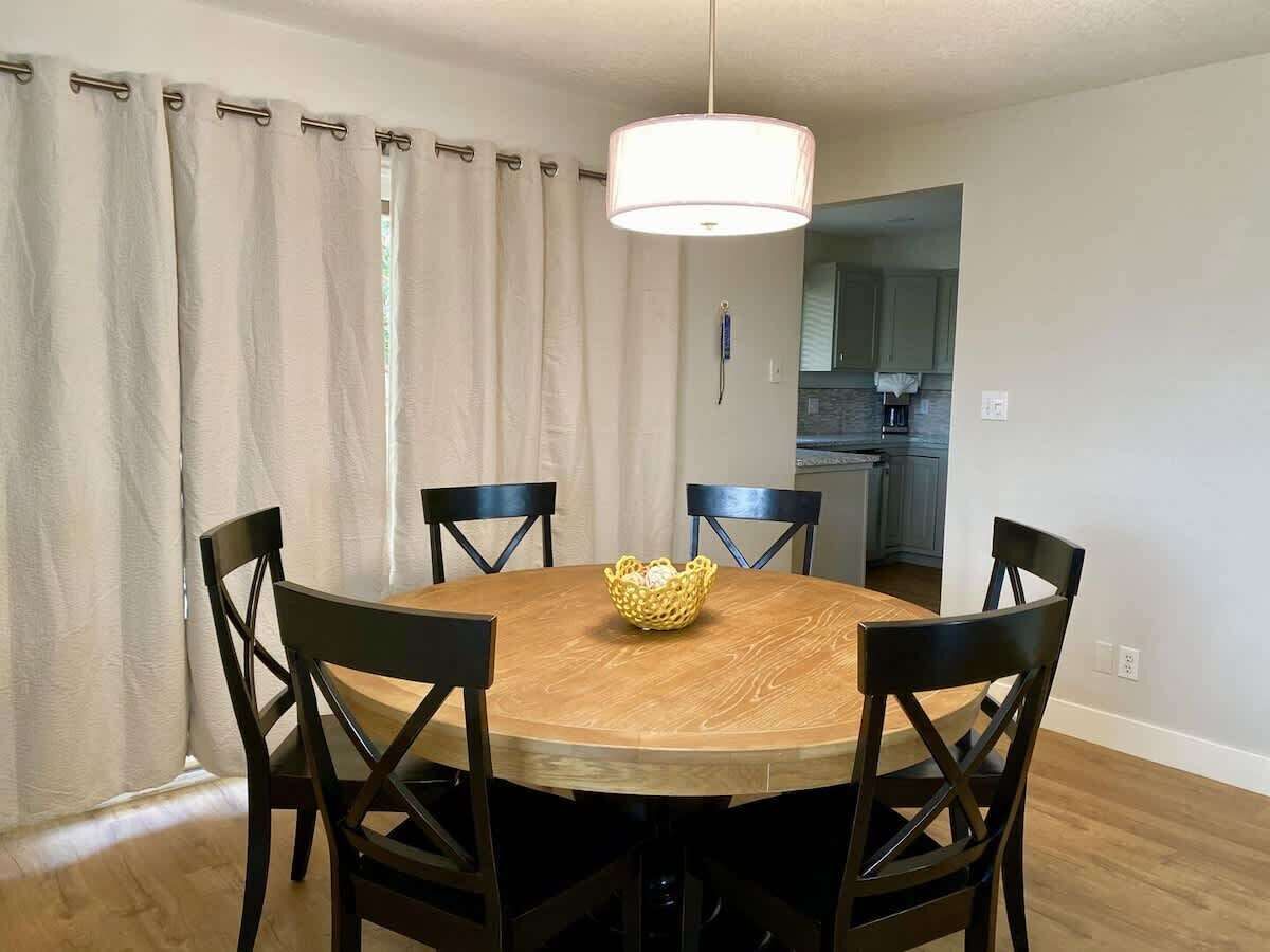A dining area with a round wooden table, six chairs, and a hanging light fixture.