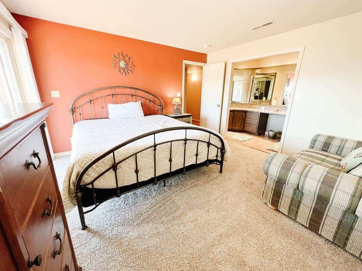 A bedroom with a bed, dresser, and a sofa.
