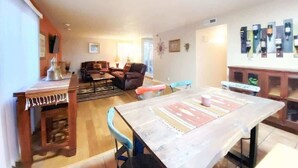 A spacious living area with a dining table, sofas, and a kitchen area.