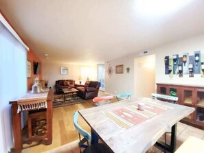 A spacious living area with a dining table, sofas, and a kitchen area.