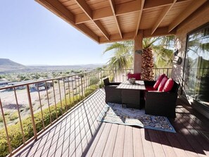 A balcony with a wooden ceiling, wicker furniture, and a view of a desert landscape.