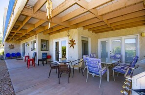 Ein möblierter Patio-Bereich mit Sitzgelegenheiten und Tisch, ein überdachter Bereich mit Holzboden und Blick auf die umliegende Landschaft.