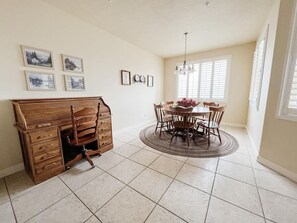 A dining area with a wooden table and chairs, a dresser, and a chandelier.