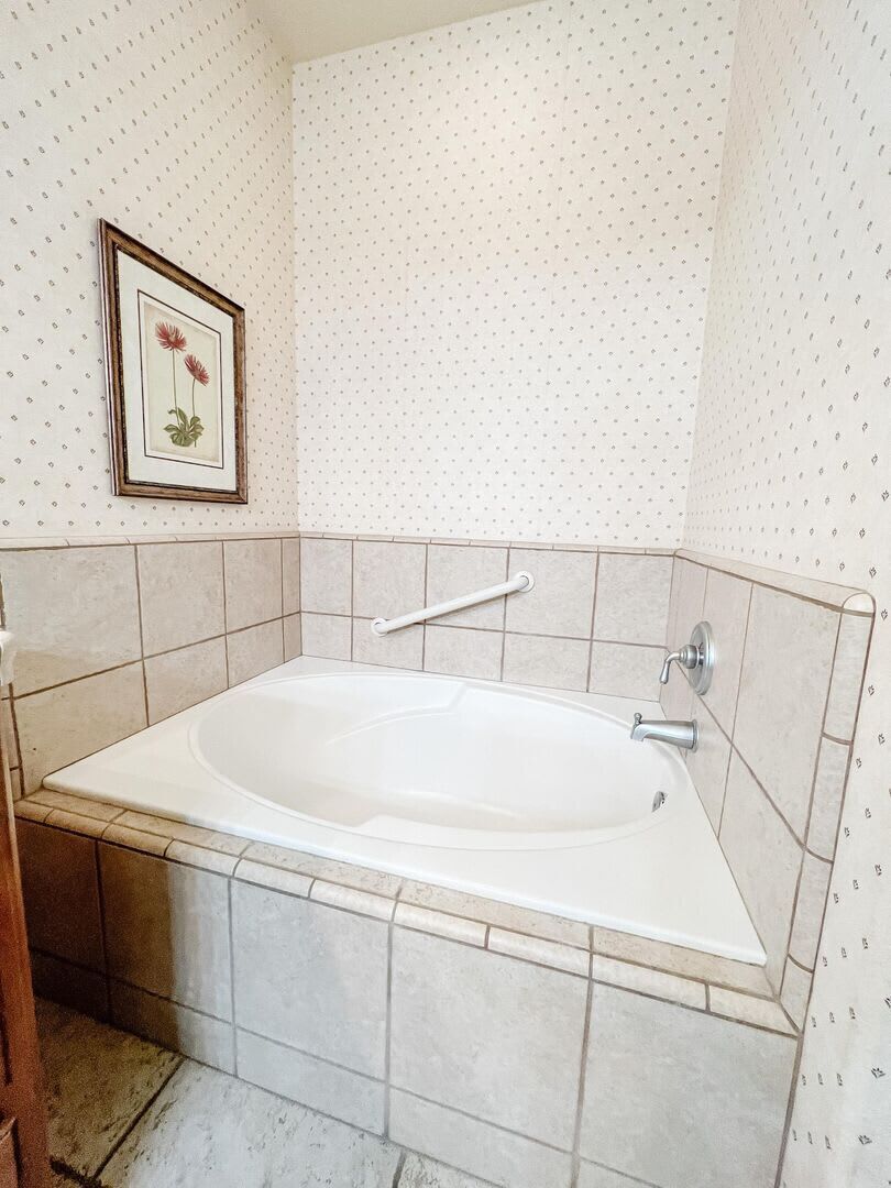 A bathroom with a freestanding bathtub, tiled walls, and a framed picture on the wall.