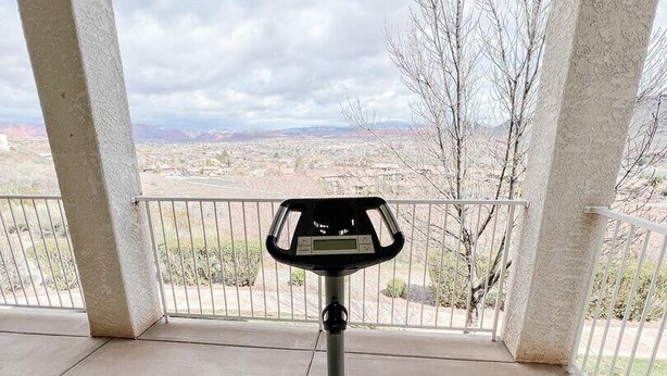 A stationary exercise bike on a covered outdoor area with a view of a landscape.