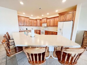A kitchen with a large island, wooden cabinets, and a white refrigerator.