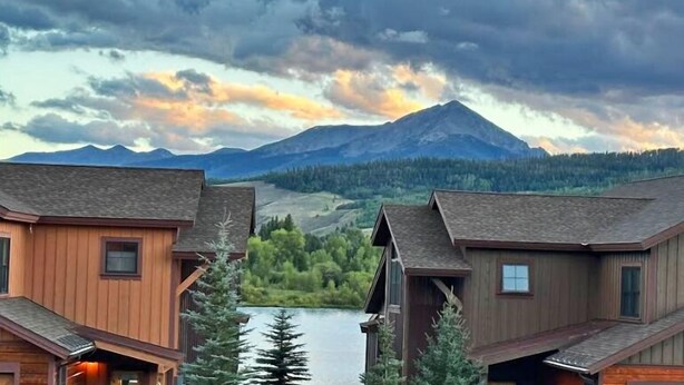 Una hilera de cabañas de madera con una montaña y un lago al fondo.