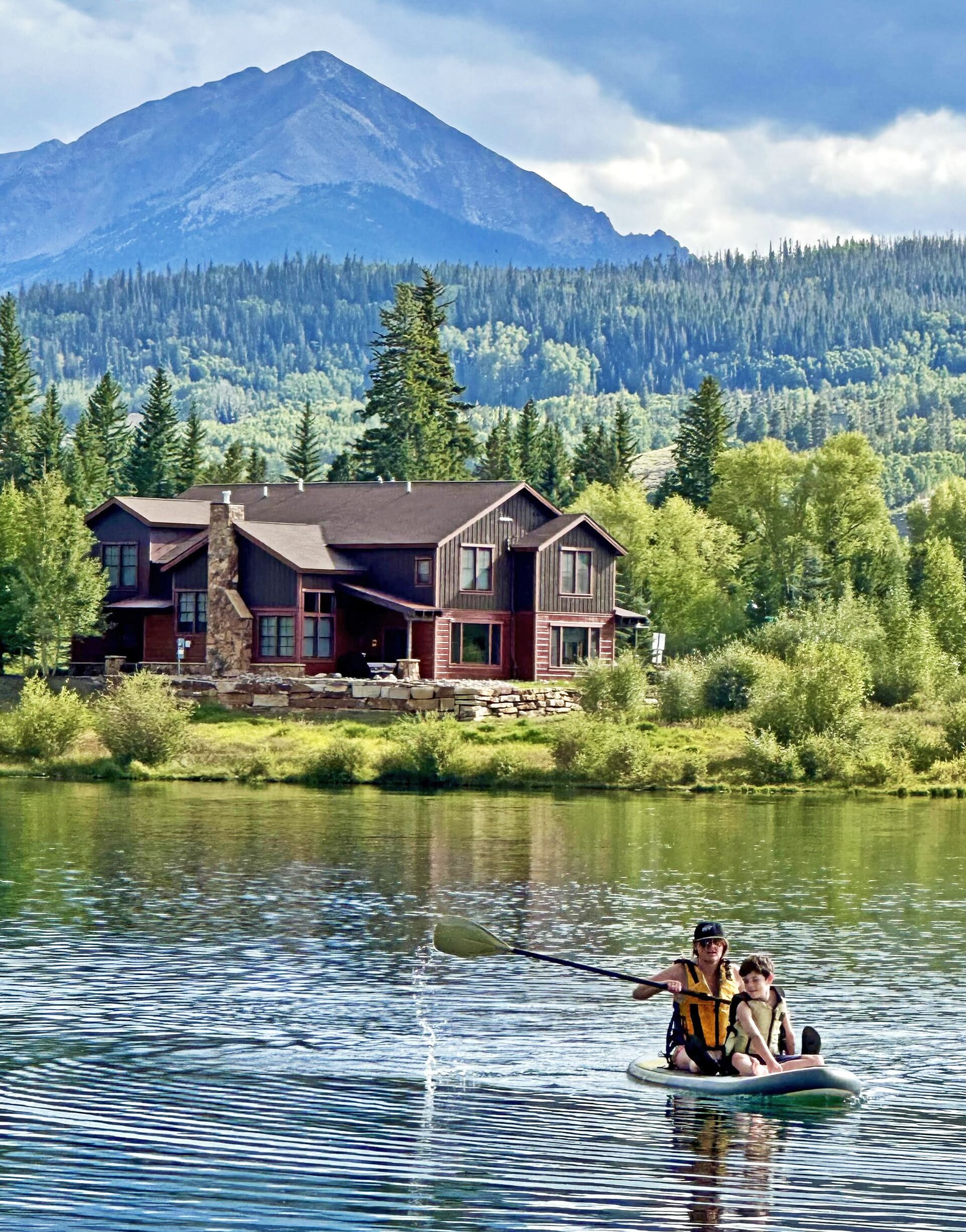A house by a lake with a mountain in the background.