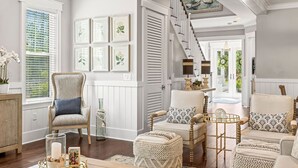 A spacious living room with a high ceiling, a staircase, and a view of the outdoors. - Coastal Elegance at NatureWalk: Modern Retreat Minutes from the beach! (Santa Rosa Beach)