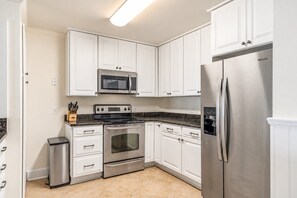A modern kitchen with white cabinetry, stainless steel appliances, and a granite countertop.