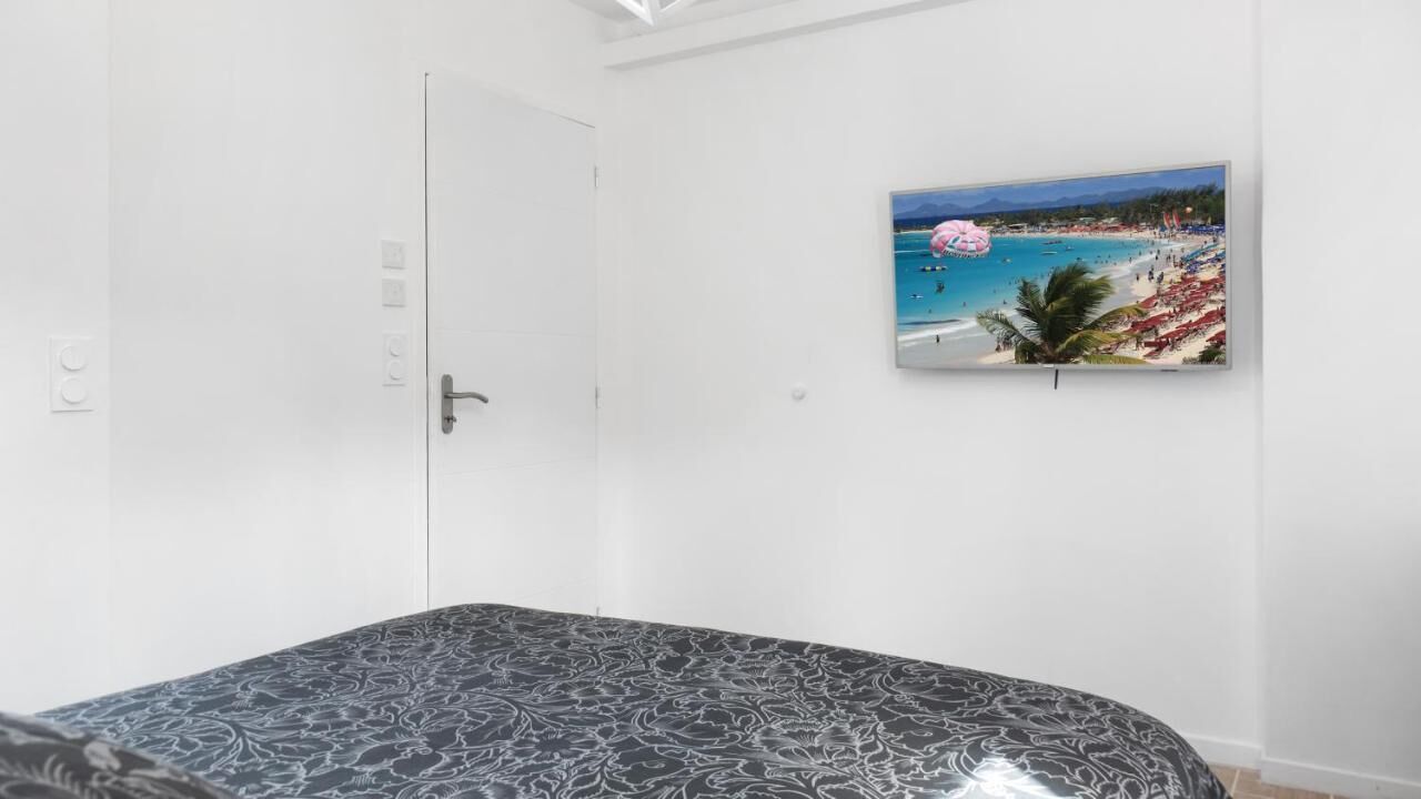 A bedroom with a bed, a white door, and a beach scene painting on the wall.