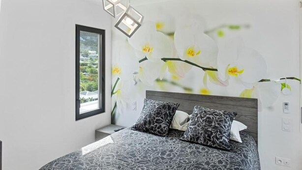 Un dormitorio con una cama grande, una ventana y una pared decorada con un mural floral.