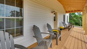 A covered porch with Adirondack chairs and a wooden deck. - Timeless Hillsville Farmhouse: Blue Ridge Parkway! (Hillsville)