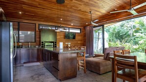 Eine moderne Küche mit Holzausstattung, einer großen Kochinsel und einem Essbereich mit einer Couch und Stühlen.