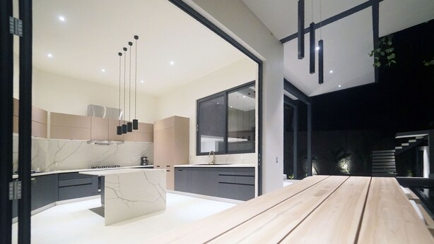 Una cocina moderna con una mesa de comedor de madera, electrodomésticos integrados y un ventanal grande.