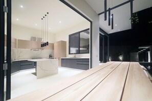 A modern kitchen with a wooden dining table, built-in appliances, and a large window. - Santa Teresa (Cobano)