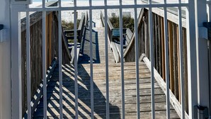 A gate with a large 'M' sign, leading to a wooden boardwalk with a view of the beach and ocean. - Ground Floor, Close to Beach, Pet Friendly Free Wifi/Beach Svs 2 Pools, New Mgmt (Miramar Beach)