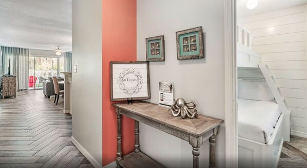 Een hal met een houten console waarop ingelijste foto's en een decoratief object staan, leidend naar een witte trap.