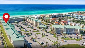 An aerial view of a resort with multiple buildings, a parking lot, and a beach in the background. - Ground Floor, Close to Beach, Pet Friendly Free Wifi/Beach Svs 2 Pools, New Mgmt (Miramar Beach)